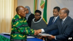 FILE - President John Magufuli, left, who seeks a second five-year term, hands over his electoral nomination form to Chairman of the National Electoral Commission (NEC) Judge Semistocles Kaijage, right, in Dodoma, Tanzania, Aug. 25, 2020. 