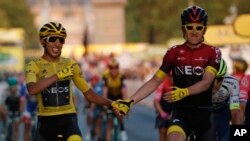 Colombia's Egan Bernal wearing the overall leader's yellow jersey, left, holds hands with Britain's Geraint Thomas after winning the Tour de France cycling race in Paris, France, July 28, 2019.
