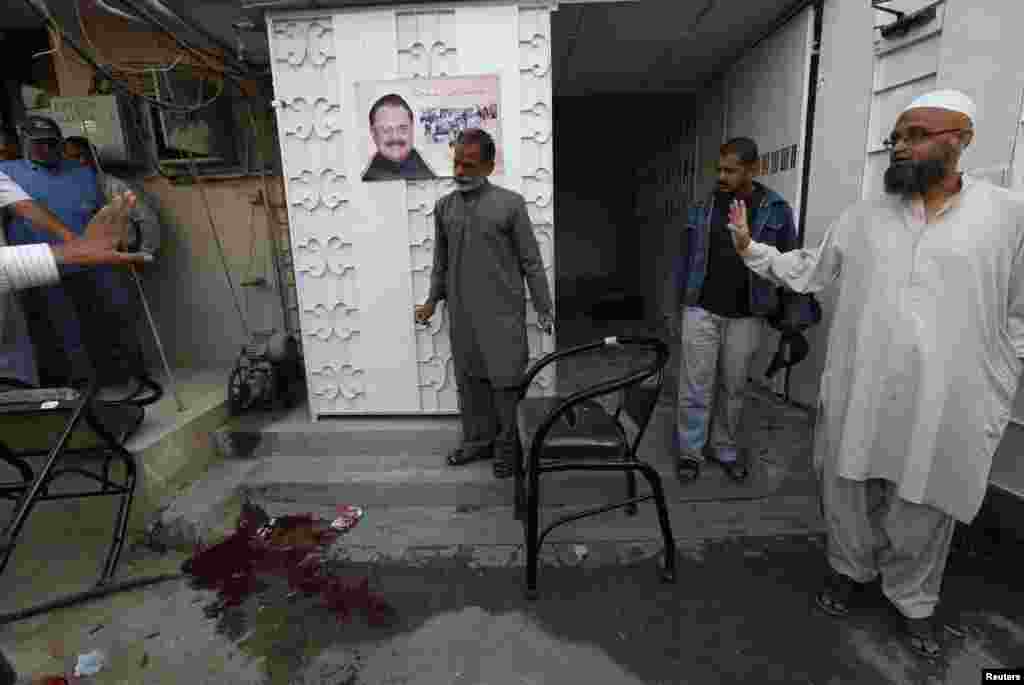 Residents look at blood stains on the ground outside the Muttahida Qaumi Movement (MQM) political party office after it was raided by paramilitary forces in Karachi, March 11, 2015.