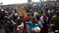 People wait to receive food and supplies from an aid distribution point set up inside a makeshift camp housing an estimated 100,000 displaced people, at Mpoko Airport in Bangui, Central African Republic, Jan. 7, 2014. 