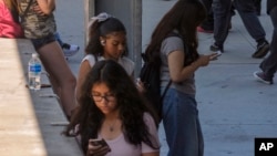 FILE - Students use their cellphones as they leave for the day the Ramon C. Cortines School of Visual and Performing Arts High School in Los Angeles, California, Aug. 13, 2024. 