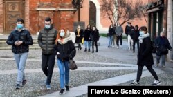 Orang-orang mengenakan masker berjalan-jalan di alun-alun Kota Codogno, Italia, satu tahun setelah kota itu menjadi pusat wabah pandemi COVID-19 di Eropa, 11 Februari 2021. (Foto: Flavio Lo Scalzo/Reuters)