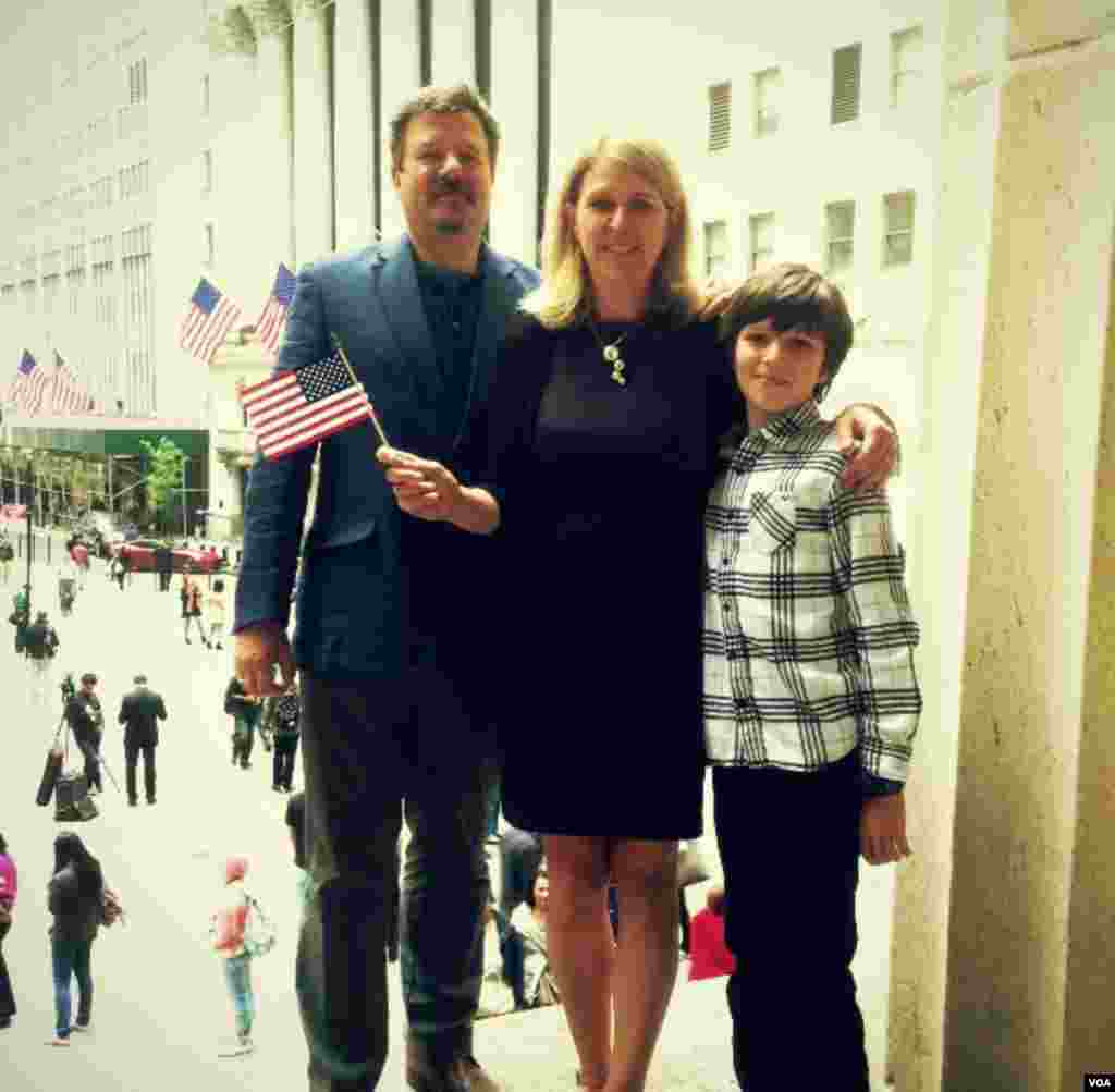 Usai upacara naturalisasi, Lesya Lysyj bersama suaminya Bo dan putranya Lev berpose di tangga Balai Federal dengan latar belakang Bursa Saham New York (22/5).&nbsp;(VOA/Adam Phillips)