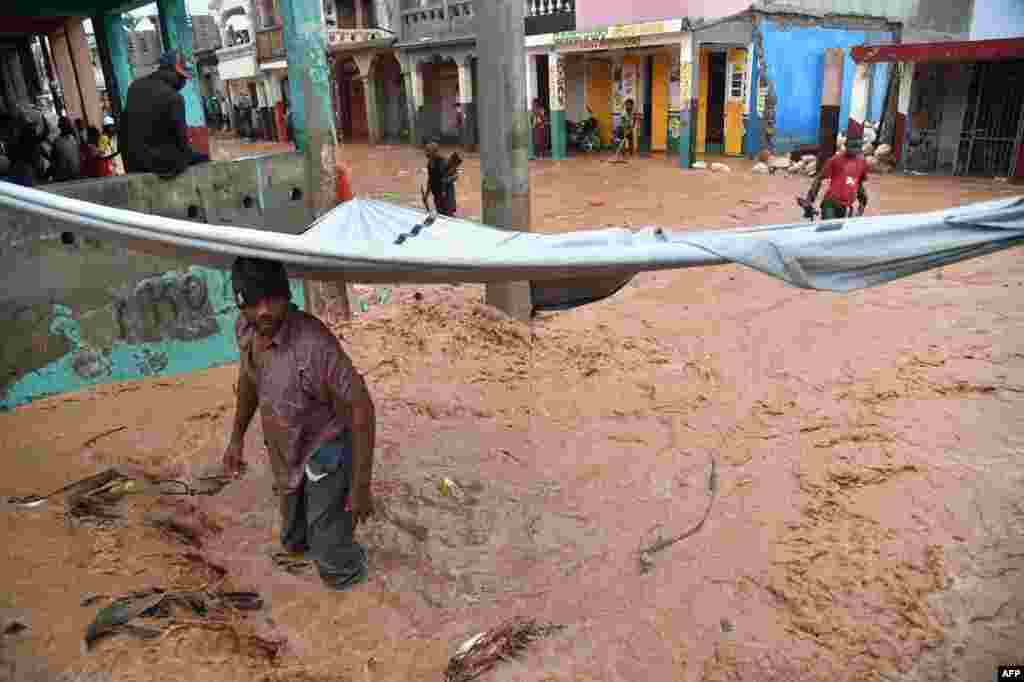 A man tries to clear debris from a partially flooded street during a seasonal storm in the commune of Jeremie, southwestern Haiti, Nov. 5, 2016. Jeremie is one of the cities hit hard by Hurricane Matthew.