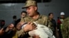 A soldier holds a baby as Turkish citizens evacuated from Lebanon disembark from the TCG Bayraktar war ship after its arrival at the southern Turkish port of Mersin on Oct. 10, 2024.