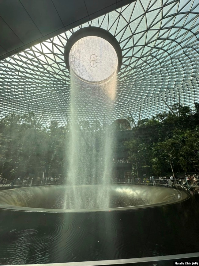 An indoor waterfall is situated in a five-story high indoor forest filled with trees and plants at Changi Jewel Airport in Singapore. (Natalie Chin via AP)