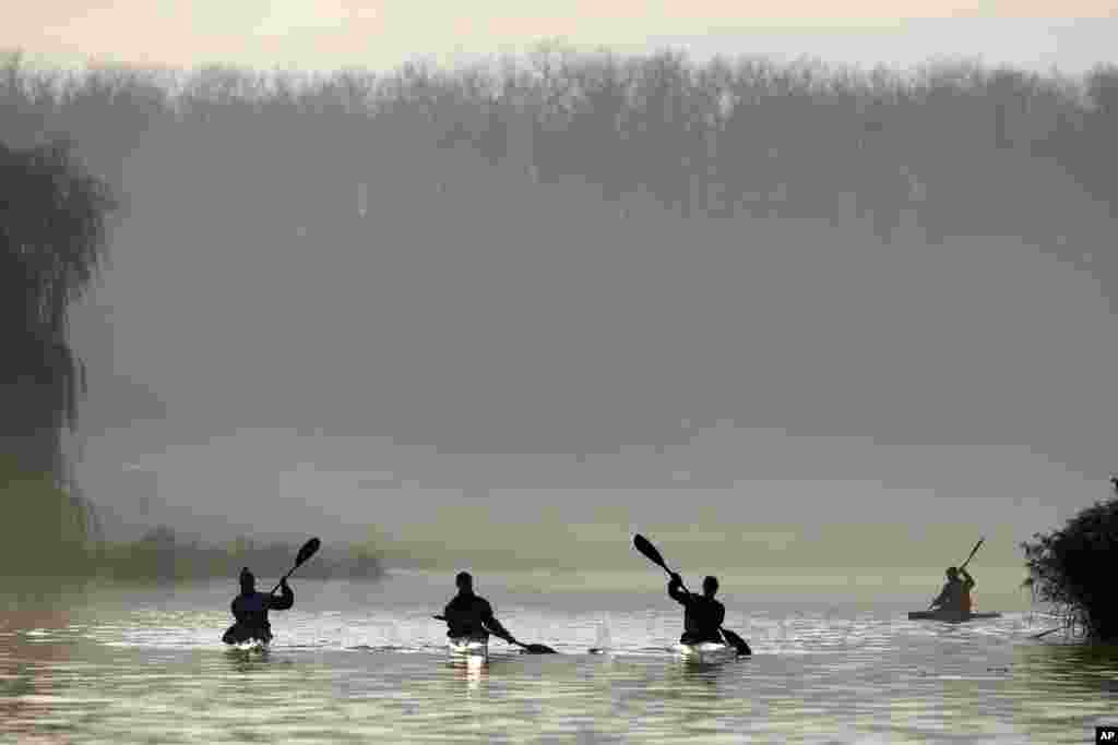 Rowers make their way on Komsomolskoye lake in Minsk, Belarus, at sunrise.