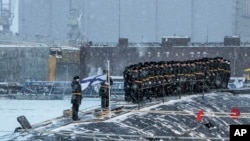 Russian sailors stand on the deck of the nuclear submarine The Emperor Alexander III while Russian President Vladimir Putin attends a flag-raising ceremony for newly built nuclear submarines at the Sevmash shipyard in Severodvinsk in Russia's Archangelsk region, Dec. 11, 2023. 
