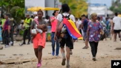 Un migrante lleva una bandera venezolana en Necoclí, Colombia, un punto de parada para los migrantes que toman barcos hacia Acandí que conducen al Tapón del Darién, el jueves 13 de octubre de 2022.