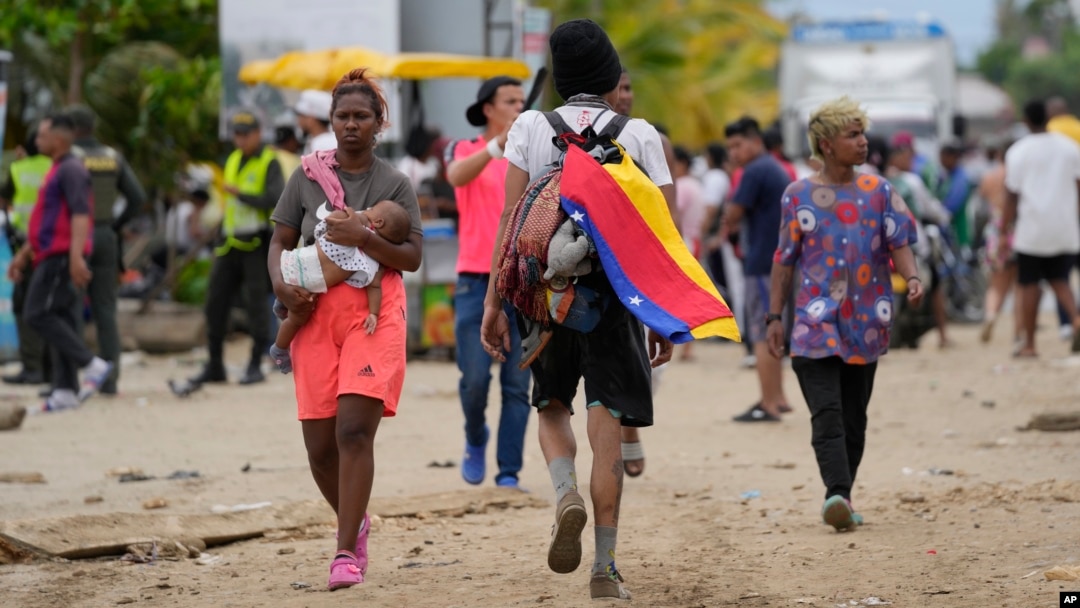 ARCHIVO - Un migrante porta una bandera venezolana en Necoclí, Colombia, un punto de parada para los migrantes que toman barcos a Acandi que conduce al Tapón del Darién, el jueves 13 de octubre de 2022.