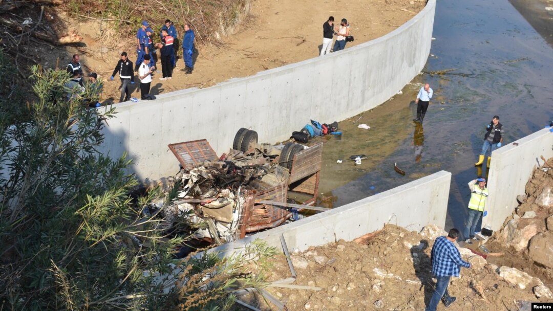 Warga melihat rongsokan truk migran yang terguling dari sebuah jembatan di Izmir, Turki, Minggu (14/10). 