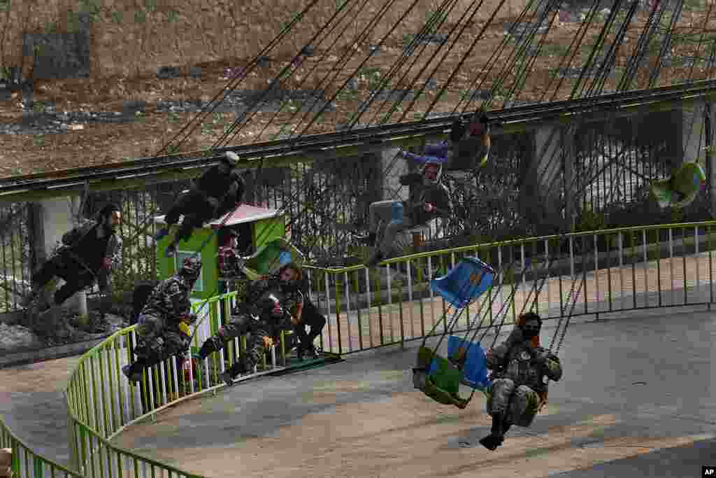 Taliban fighters and other Afghan men ride a swing at an amusement park, in Kabul, Afghanistan.