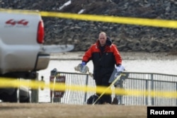 Seorang petugas tanggap darurat membawa puing-puing setelah penerbangan American Eagle 5342 bertabrakan dengan helikopter Black Hawk dan jatuh ke Sungai Potomac, Arlington, Virginia, 30 Januari 2025. (Foto: Kevin Lamarque/Reuters)