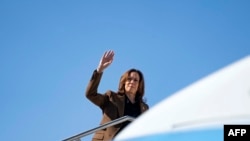 A vice-presidente dos EUA e candidata democrata à presidência, Kamala Harris, acena enquanto embarca no Air Force Two no Aeroporto Internacional Sky Harbor em Phoenix, Arizona, a 11 de outubro de 2024. 