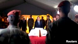 French President Francois Hollande (C) pays tribute near a flag-draped coffin bearing one of two French soldiers who was killed overnight, in Bangui, Dec. 10, 2013. 