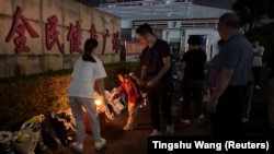 Orang membakar dupa di dekat karangan bunga di luar pusat olahraga tempat serangan tabrak lari mematikan terjadi, di Zhuhai, Guangdong, China, 12 November 2024. (Foto: Tingshu Wang/REUTERS)