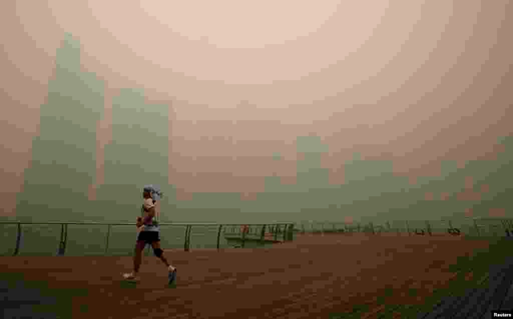 A man jogs along the deserted Marina Promenade as the skyline of Singapore&#39;s central business district is covered in haze.&nbsp; Haze from fires in Indonesia blanketing Singapore could persist for weeks or longer, as the smoke drove air quality to &quot;hazardous&quot; levels.