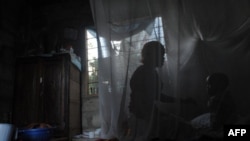 A mother and her child sit on a bed covered with a mosquito net near Bagamoyo, 70 km north of Tanzanian capital Dar es Salaam.