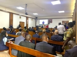 A court in process hears a bail application of human rights lawyer Nicholas Opio, on screen, who faces charges of money laundering, in Kampala, Uganda, Dec. 30, 2020. (Halima Athumani/VOA)