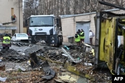 Trabajadores comunales limpian escombros en el patio de un edificio residencial dañado luego de un ataque con misiles en Járkov el 25 de noviembre de 2024.