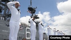 Marineros asignados al barco de asalto anfibio USS America saludan el Memorial USS Missouri y el Memorial USS Arizona a su paso por Pearl Harbor, Hawaii, el 30 de junio de 2016.