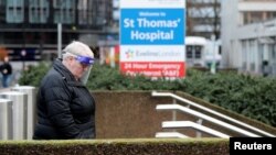 FILE - A person wearing personal protective equipment walks outside St Thomas' Hospital in London, Dec. 12, 2021.