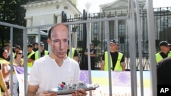 A man wears a mask depicting Russian President Vladimir Putin, during a protest against Russia's behavior in Ukraine in front of the Russian Embassy in Warsaw, July 27, 2014. 