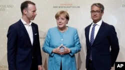 From left, Handelsblatt chief editor Sven Afhueppe, German Chancellor Angela Merkel and the Handelsblatt publisher Gabor Steingart pose for a photo prior to the 'Deutschland Live' event organized by the economy news paper 'Handelsblatt' in Berlin, Aug. 23, 2017.