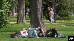 ARCHIVO - Varias personas descansan en el parque del Retiro el miércoles 20 de marzo de 2024, en Madrid, España.