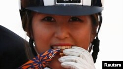 Chung Yoo-ra, yang juga dikenal sebagai Chung Yoo-yeon, menggigit medali emas yang diperolehnya seusai memenangkan kompetisi berkuda dalam nomor equestrian Dressage Team pada Asian Games ke-17 di Dream Park Equestrian, Incheon, Korea Selatan, 20 September 2014. (REUTERS/Kim Hong-Ji/File) 