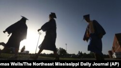 In this June 27, 2020, file photo, Saltillo High School seniors make their way to the football field as the sun begins to set for their graduation ceremony in Saltillo, Mississippi.