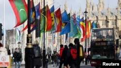 FILE PHOTO: People ride a bus past flags representing Commonwealth countries next to Westminster Abbey in London