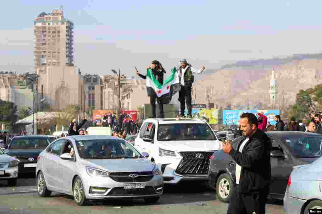 Men hold a Syrian opposition flag on the top of a vehicle as people celebrate after Syrian rebels announced that they have ousted President Bashar al-Assad, in Damascus, Dec. 8, 2024.