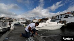 A man reinforces with ropes the mooring of his boat at a port before the arrival of Hurricane Lorenzo in Angra do Heroismo in the Azores islands, Portugal, Oct. 1, 2019. 