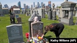 Le 10 mai 2020, Sharon Rivera ajuste des fleurs et d'autres articles laissés sur la tombe de sa fille, Victoria, au cimetière Calvary à New York, le jour de la fête des mères. Victoria est décédée d'une overdose le 22 septembre 2019, à 21 ans.