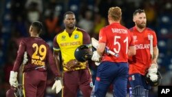 England's Phil Salt, right, and teammate Jonathan Bairstow are congratulated by West Indies' Johnson Charles and Nicholas Pooran, left, following their men's T20 World Cup cricket match at Darren Sammy National Cricket Stadium, Gros Islet, St Lucia, June 19, 2024.