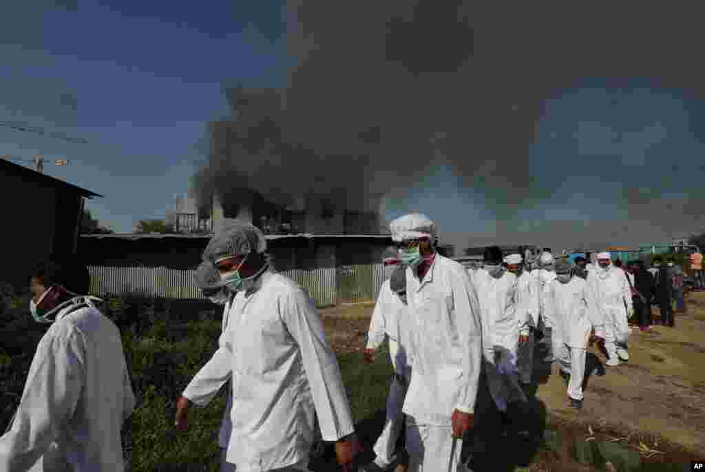 Employees leave as smoke rises from a fire at the Serum Institute of India, the world&#39;s largest vaccine maker, which is manufacturing the AstraZeneca-Oxford University vaccine for the coronavirus, in Pune, India.