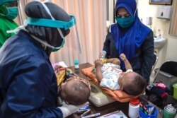 Medical staff clad in protective gears prepare to administer the vaccine for tuberculosis and oral polio vaccine for babies at a community health center in Surabaya, Indonesia on June 30, 2020.