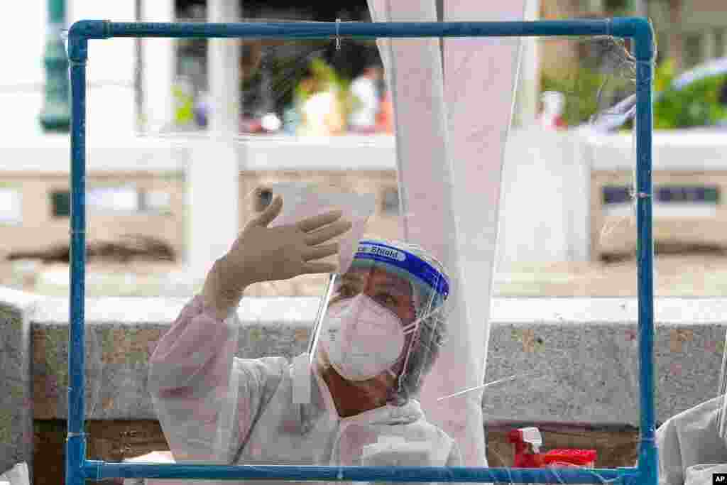 A health worker disinfects plastic sheets after collecting nasal swabs from local residents for coronavirus testing in Bangkok, Thailand.