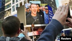 CEO Facebook, Mark Zuckerberg (tampak pada layar TV) menandai dimulainya perdagangan perdana (IPO) di bursa NASDAQ New York dengan dering bel jarak jauh dari Menlo Park, California (18/5).