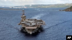 FILE - In this June 4, 2020, photo provided by the U.S. Navy, the aircraft carrier USS Theodore Roosevelt departs Apra Harbor in Guam. The carrier's strike group is now in the Middle East region, ready to defend Israel if need be.