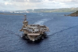 In this June 4, 2020, photo provided by the U.S. Navy, the aircraft carrier USS Theodore Roosevelt departs Apra Harbor in Guam.