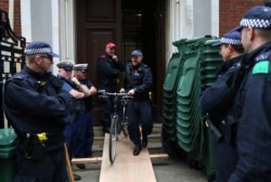 A police officer removes a bicycle outside Lambeth County Court, during a raid on an Extinction Rebellion storage facility, in London, Oct. 5, 2019.