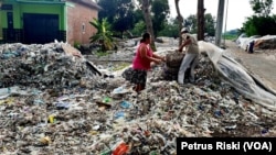 Supiati dan Saji mengangkut sampah plastik impor di pekarangan mereka, di Desa Bangun, Kecamatan Pungging, Kabupaten Mojokerto, untuk kemudian disortir dan dijual kembali. (Foto: Petrus Riski/VOA)