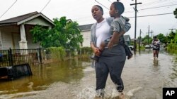 Terrian Jones reacts as she feels something moving in the water at her feet as she carries Drew and Chance Furlough to their mother on Belfast Street near Eagle Street in New Orleans after flooding from a 100-year storm from a tropical wave system in the 