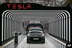 FILE - Model Y electric vehicles stand on a conveyor belt at the opening of the Tesla factory in Berlin Brandenburg in Gruenheide, Germany, March 22, 2022