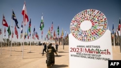 A woman walks past the emblem of the 2023 IMF and World Bank annual meetings situated at the entrance of the venue in Marrakesh on October 8, 2023.