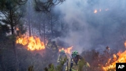 FILE - Forest firefighters work on a wildfire near the town of Jubrique, in Malaga province, Spain, Sept. 11, 2021. 