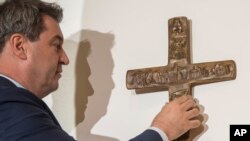 Markus Soeder, Governor of the German state of Bavaria, hangs up a cross at the entrance of the state chancellery in Munich, Germany, April 24, 2018. 
