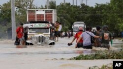 Warga wilayah San Ildefonso, propinsi Bulacan, Filipina terpaksa harus melewati jalanan yang tergenang banjir akibat hantaman Topan Nari, Sabtu (12/10). 